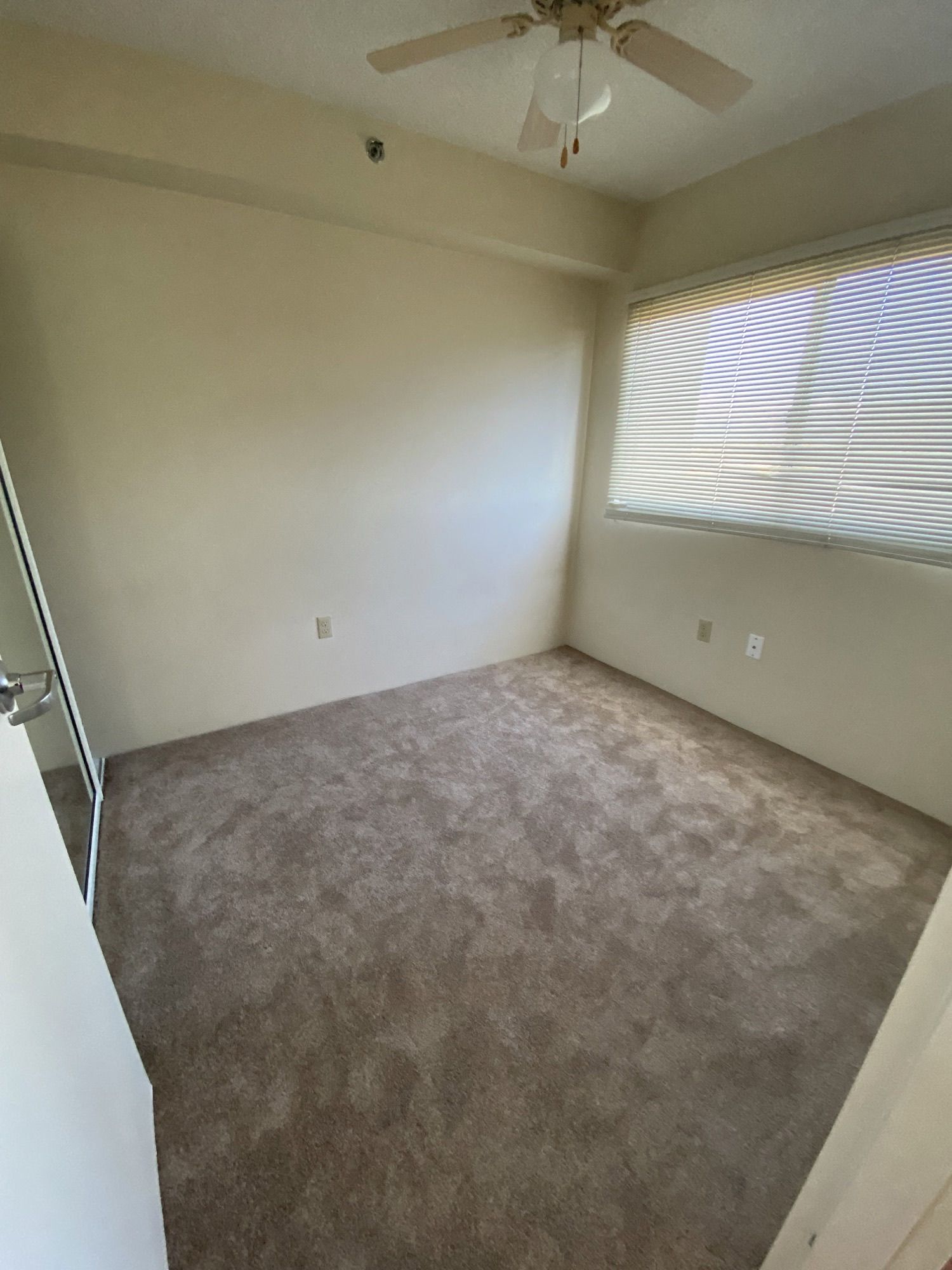 an empty room with a ceiling fan and a window